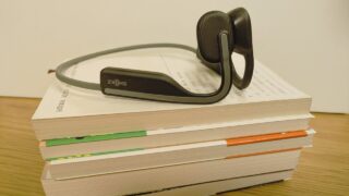 たくさんの本と骨伝導イヤホンでオーディオブックの効果を示す画像